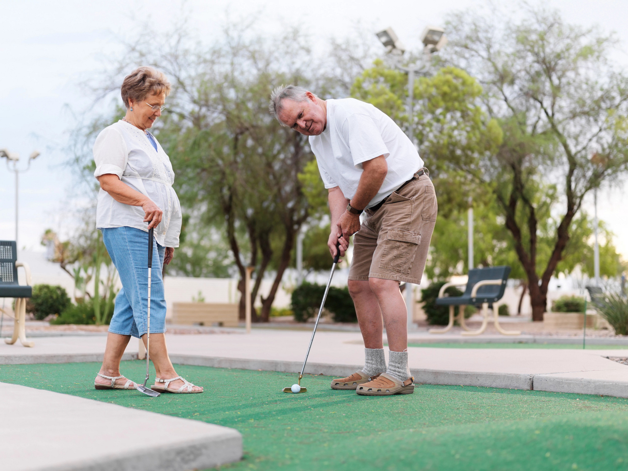 Man and a woman on a putting green playing mini golf and enjoying their time.