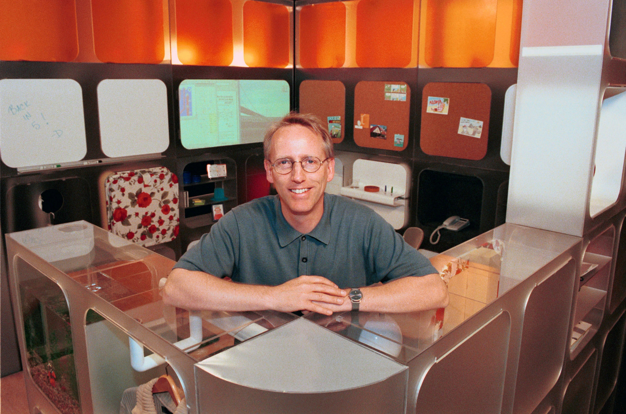 scott adams seated at a desk and smiling