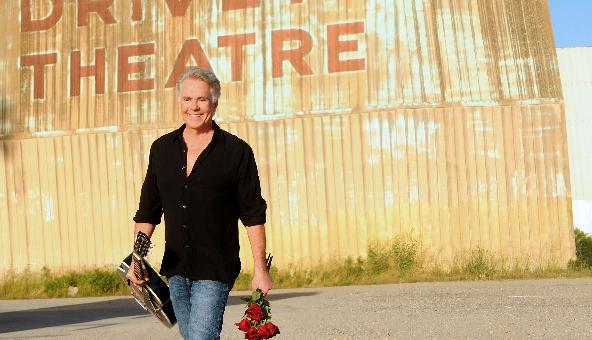At 66, Shaun Cassidy Tells All shaun cassidy smiling while walking, holding a guitar and a bouquet of roses