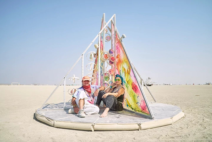 people sitting at an art installation in the desert