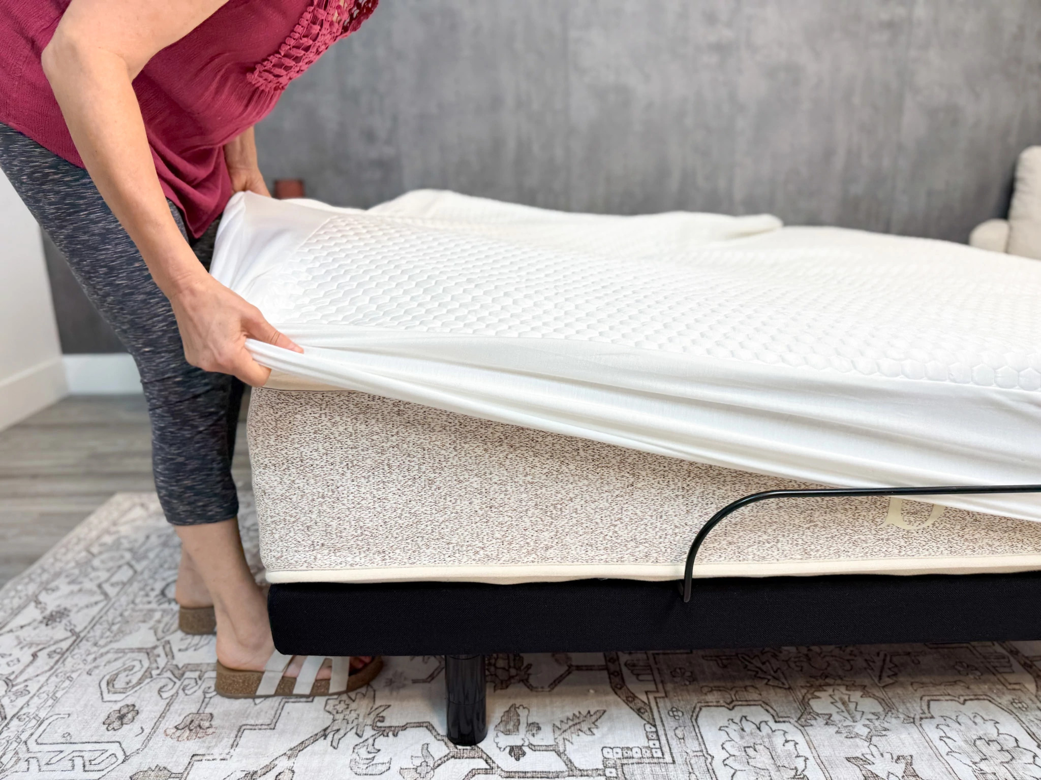 An older adult tester putting the Bear GlacioTex Protector on a bed.