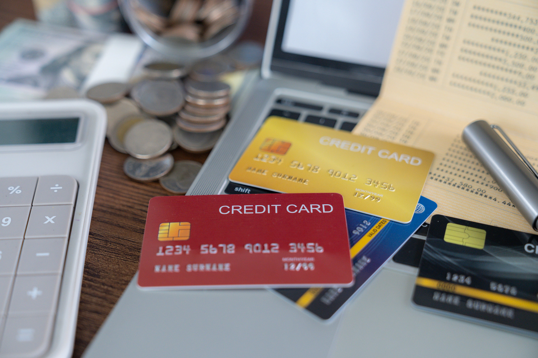 credit card stack on table with calculator, cash, and paper statement