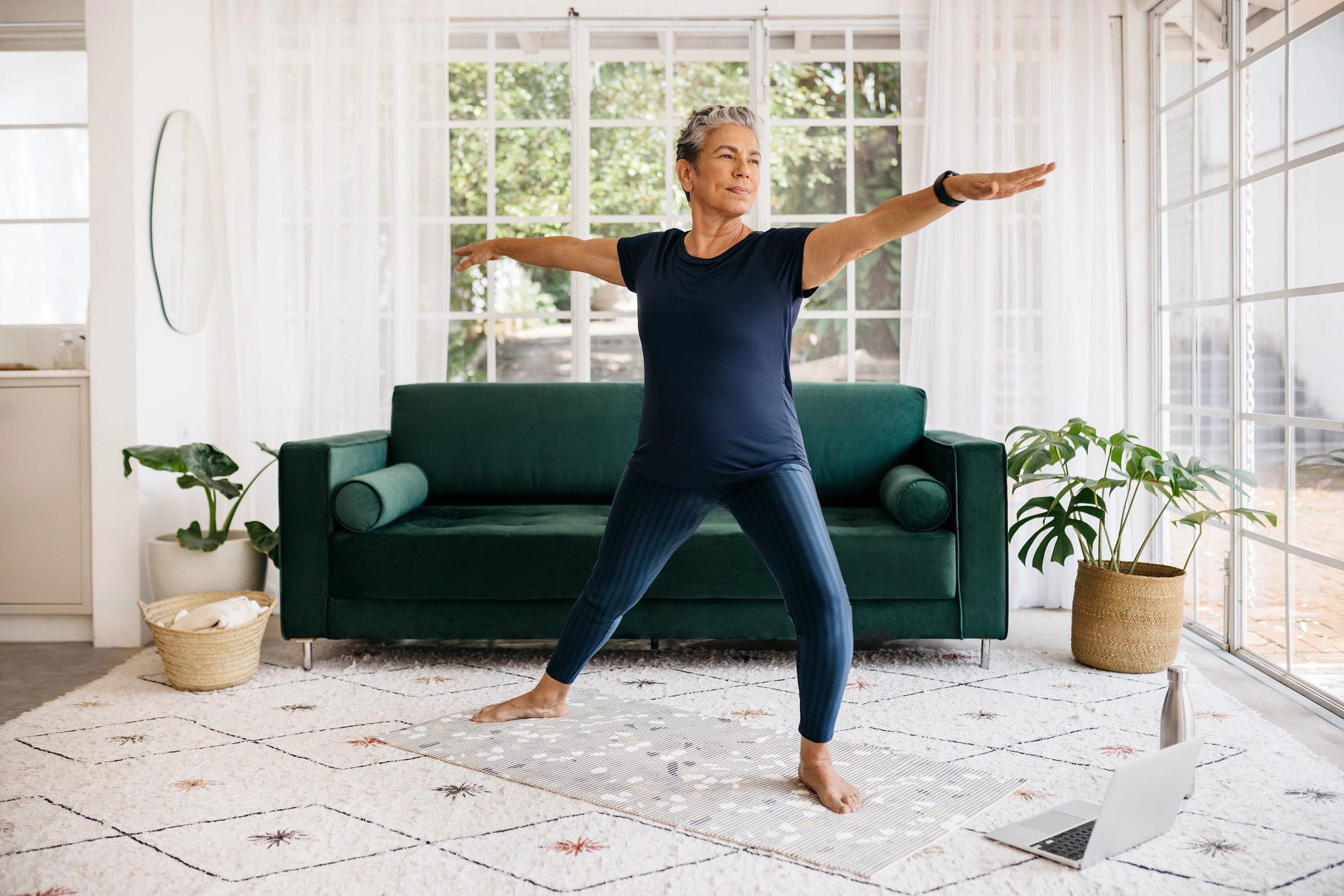 Active woman doing yoga in an online fitness class, following a healthy workout routine