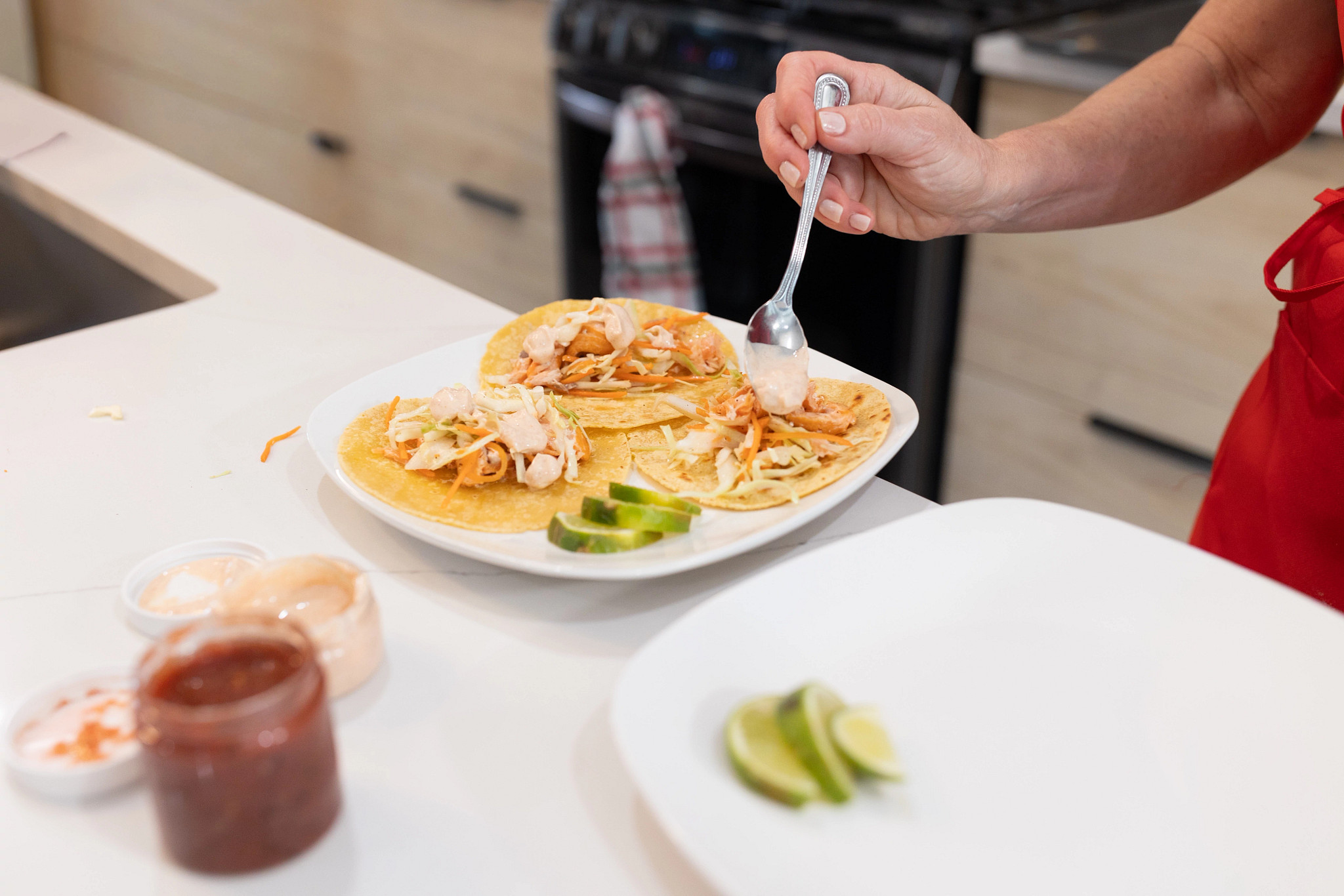 An older adult woman adding a sauce to her Sunbasket taco meal.