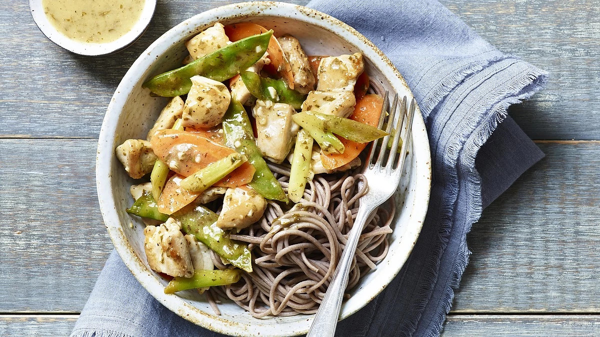 A close-up view of carrot, snow pea and chicken stir-fry in a bowl