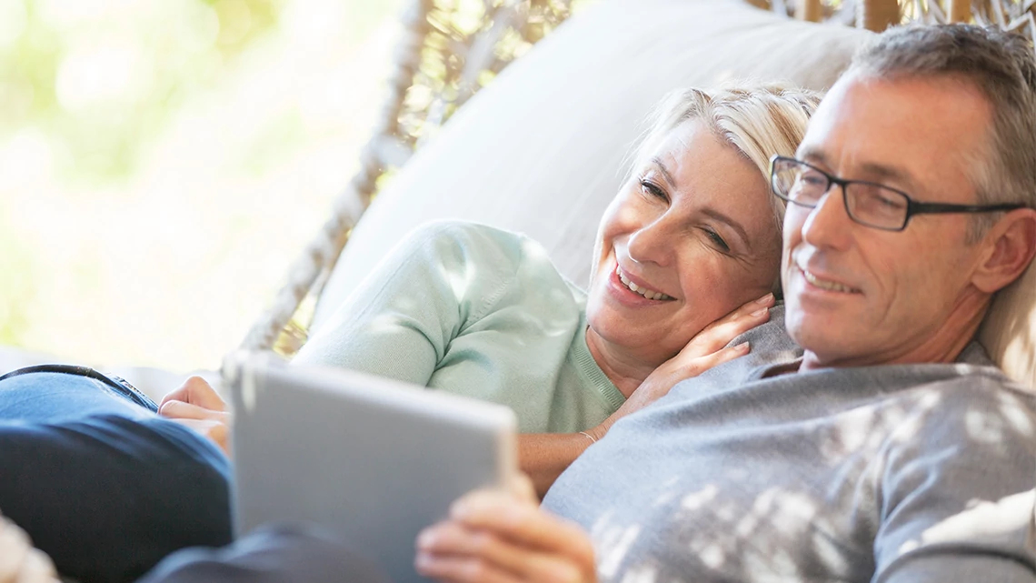 AARP® Health Savings Account offered by Optum Financial® Couple Snuggling with Laptop