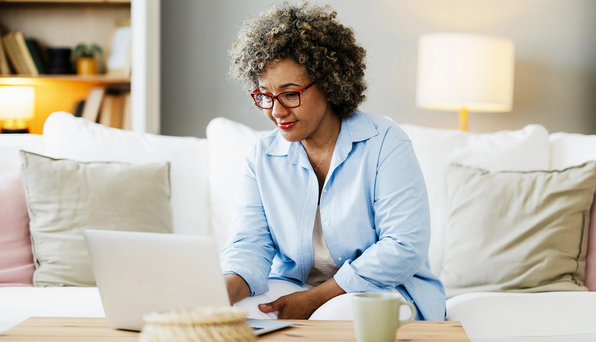 an older person sitting on a sofa while using a laptop computer