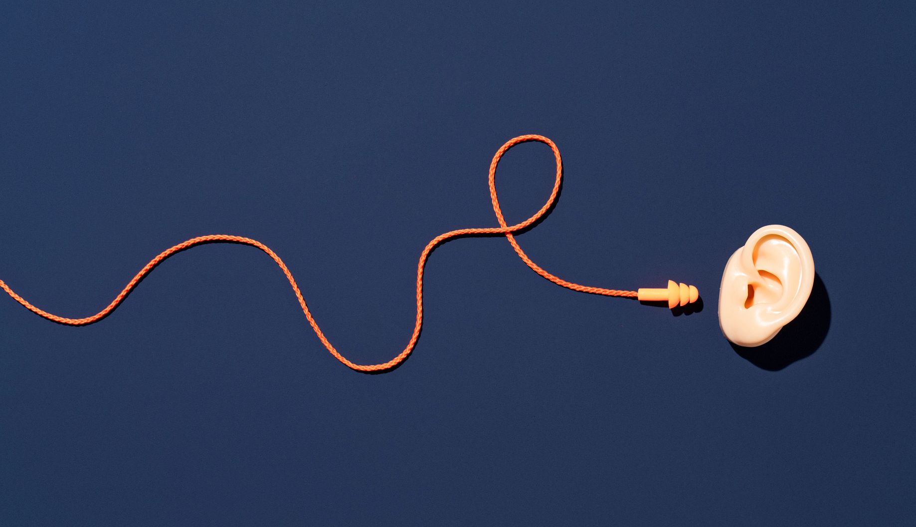 Earplugs for Hearing Protection Orange Colored Ear Plugs with Curved Strap Reach to Ear for Ear Protection on Purple Background Directly above View.