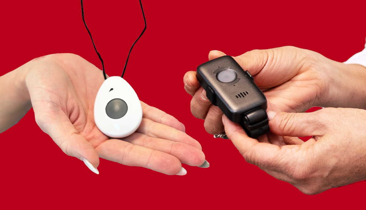 Two hands holding medical alert devices — a white pendant on the left and a black wrist monitor on the right.