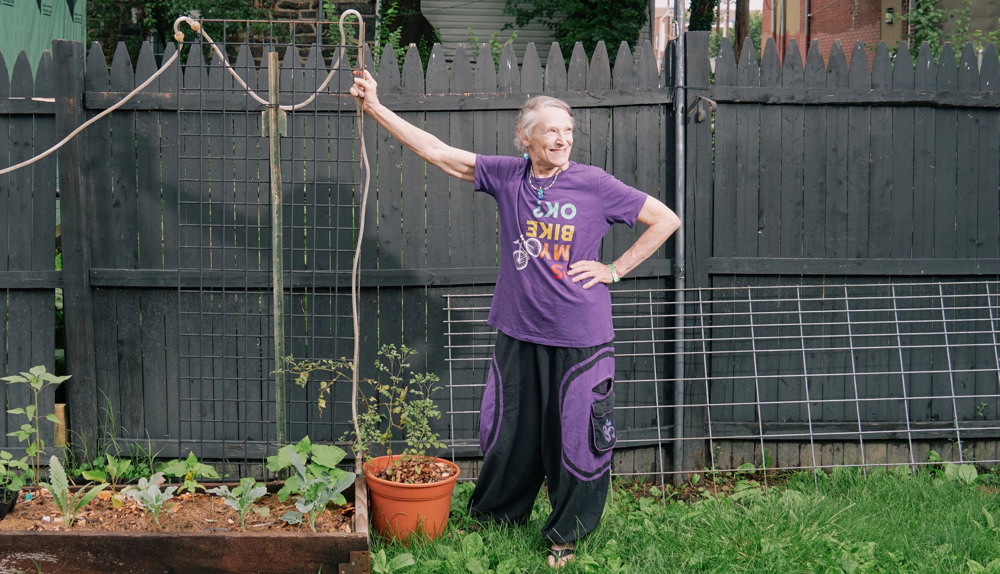 SNAP Benefit Cuts a woman in purple shirt and purple and black pants stands in a backyard garden