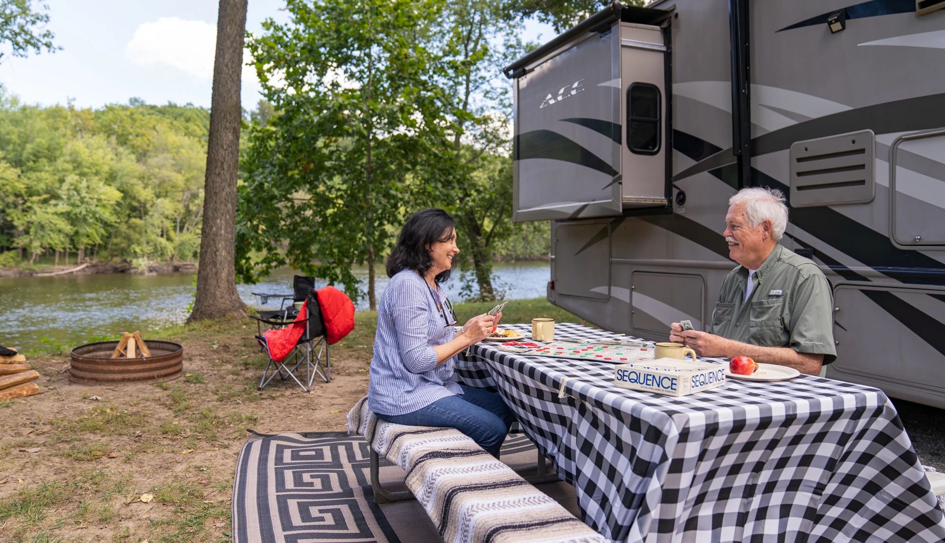 una pareja juega a las cartas en una mesa junto a una casa rodante