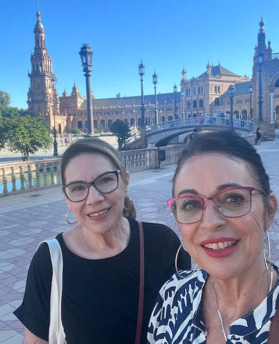 two women smiling with a building in the background