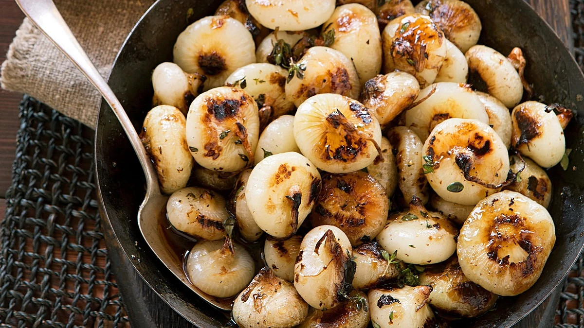 A close-up view of beer-braised cipollini onions in a pan