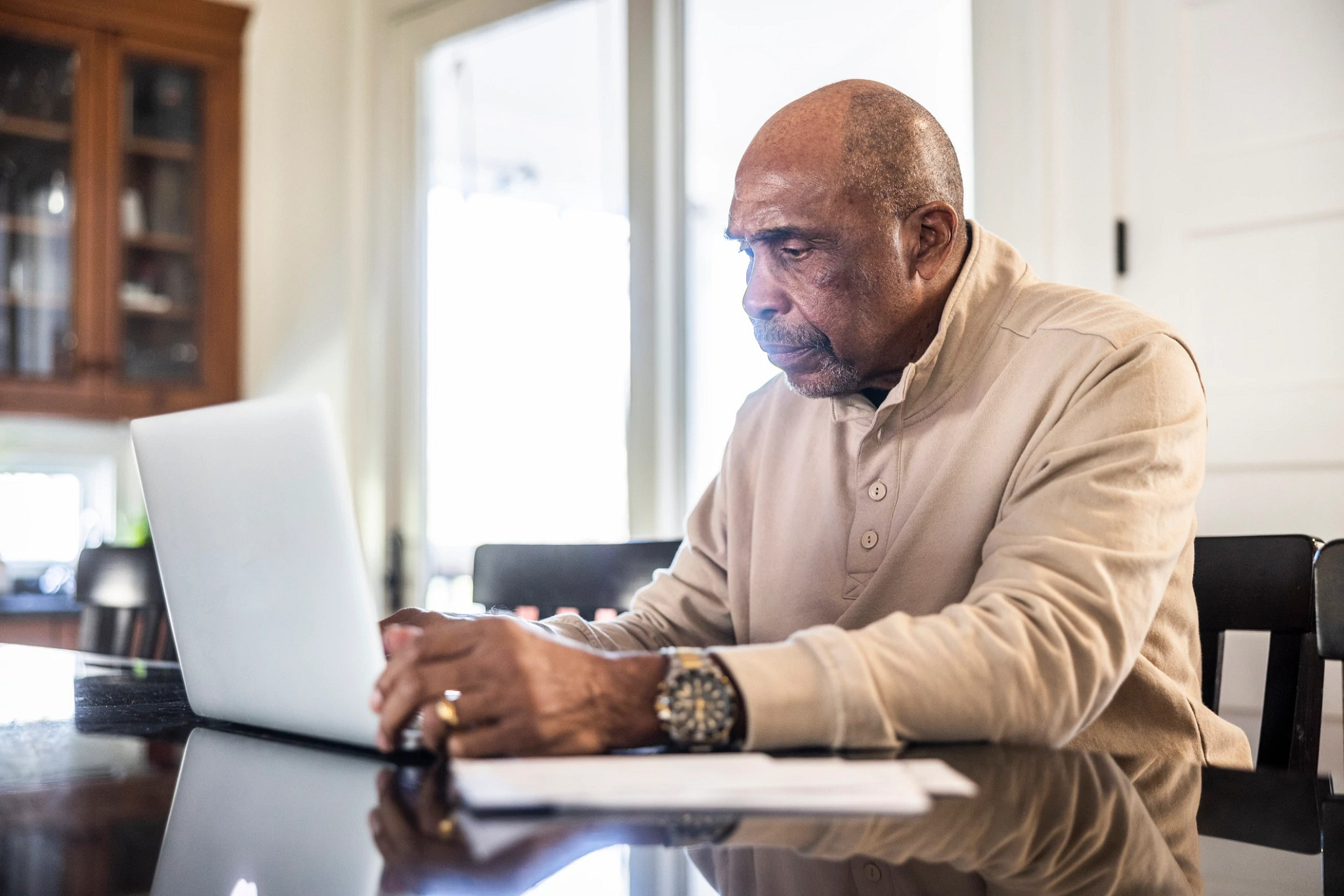 Senior man paying bills with laptop at home