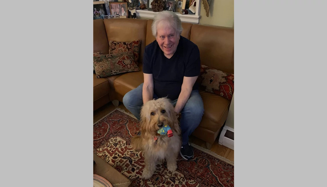 Buzz Miller sitting on a couch with his goldendoodle Ricky