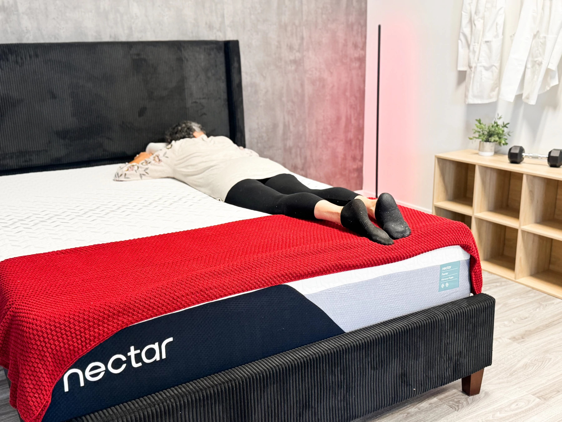 A woman lying on her stomach on a mattress with a red blanket at the end