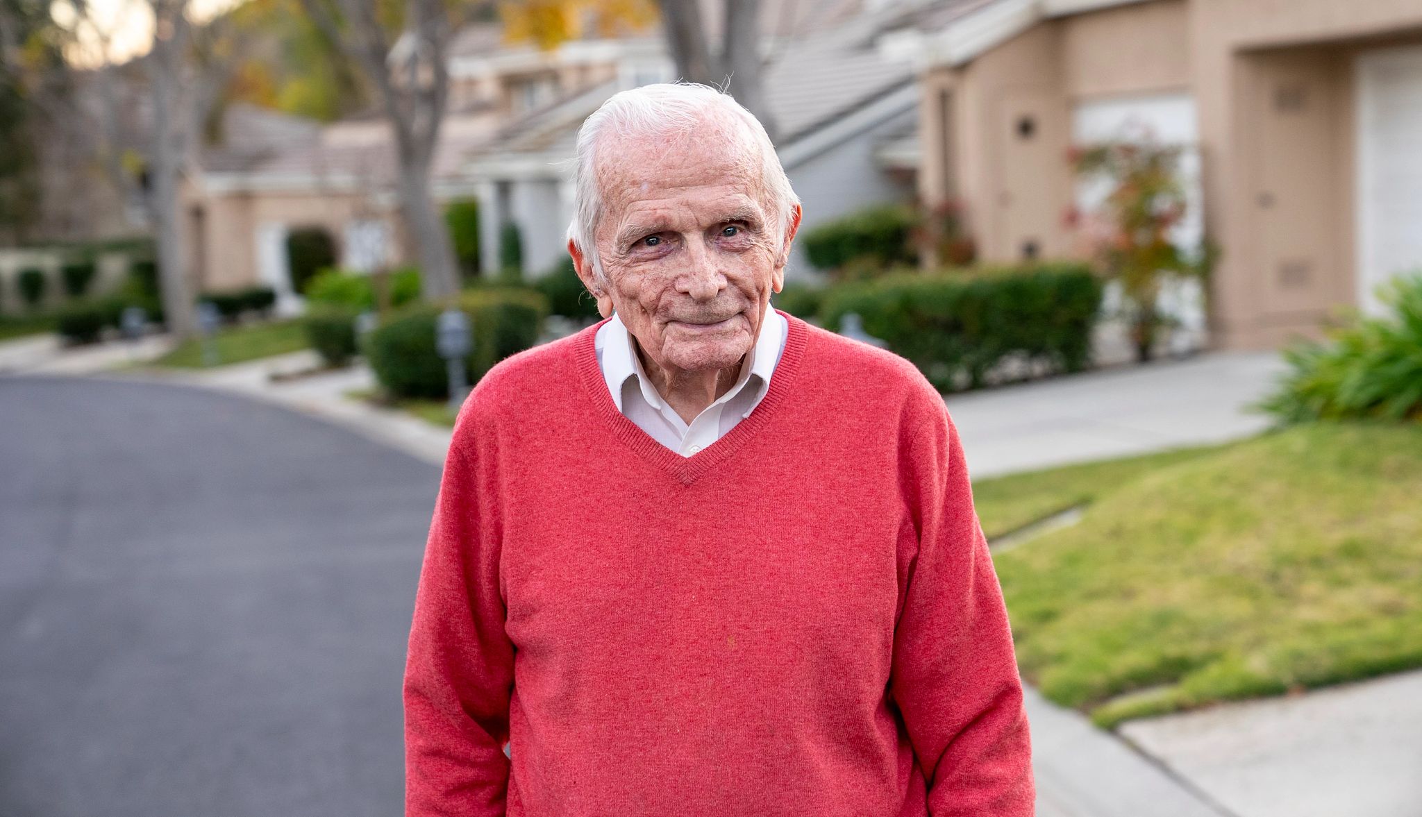 Jack Moran will be honored at Memorial Day Concert Jack Moran standing outside in red sweater in front of houses