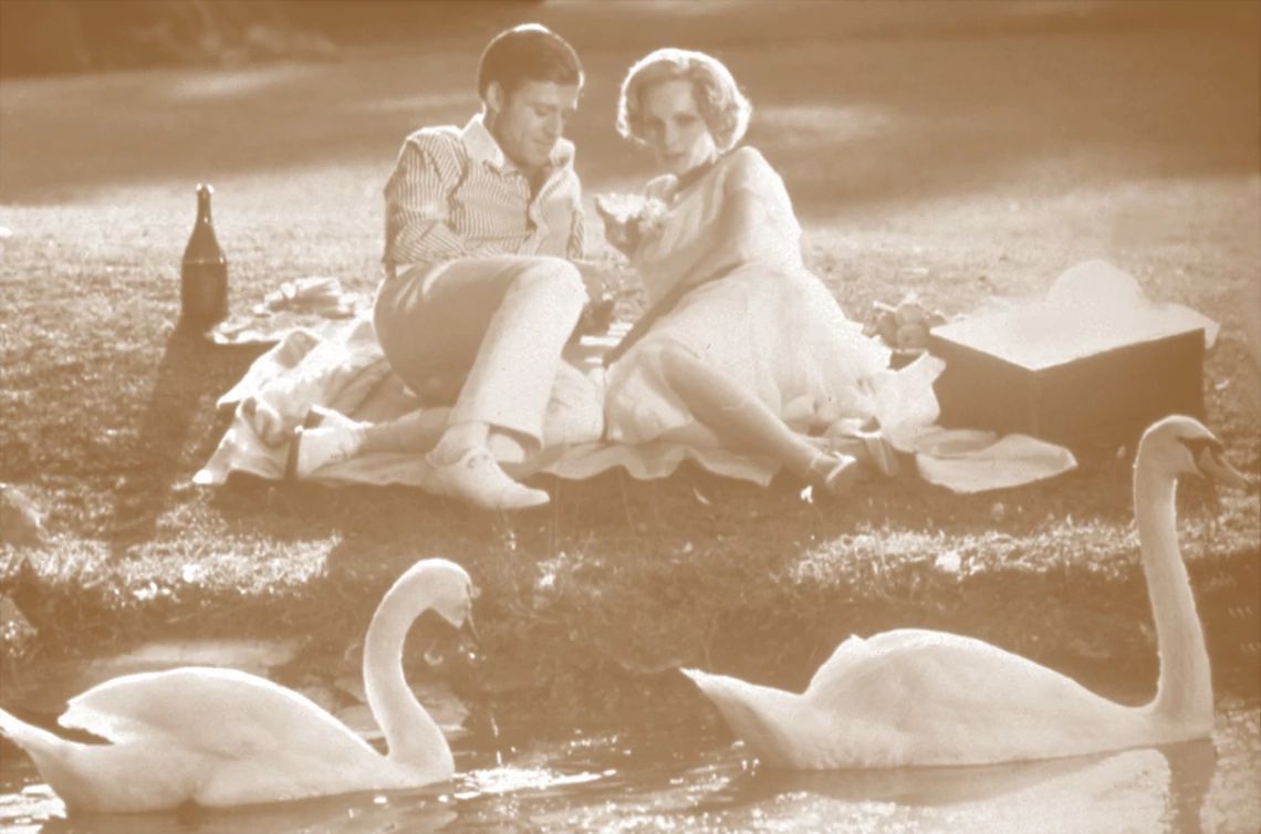 Robert Redford and Mia Farrow lying on the grass in a scene from The Great Gatsby