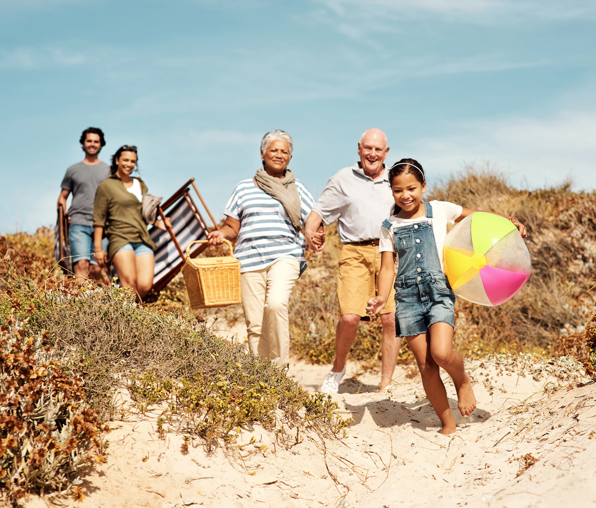 a young girl walking on the beach followed by two pairs of older adults