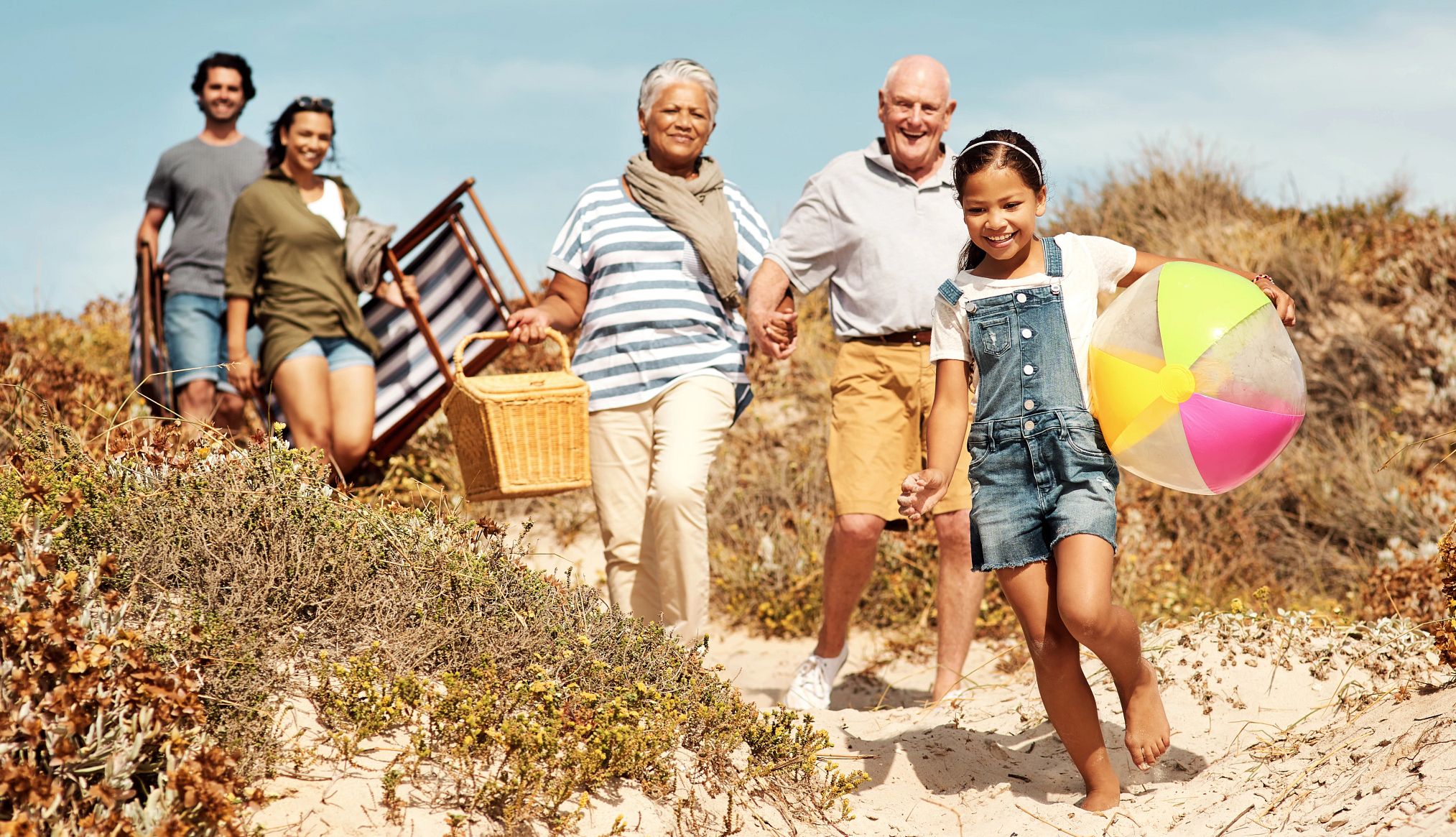 Traveling With Older Family Members a young girl walking on the beach followed by two pairs of older adults