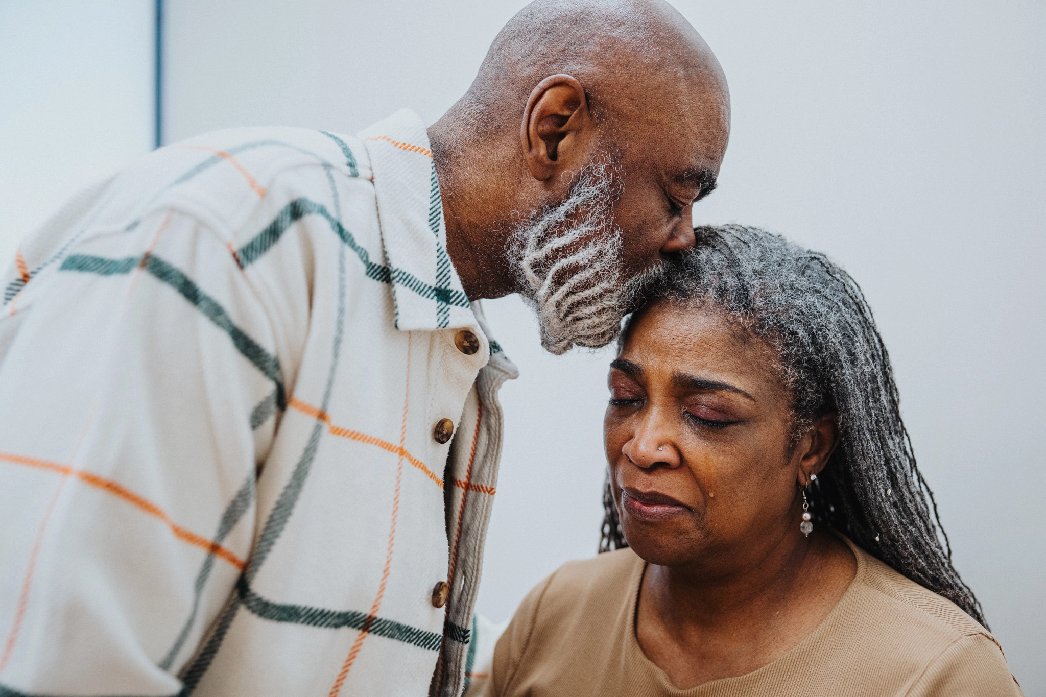 Man kissing crying woman on the forehead