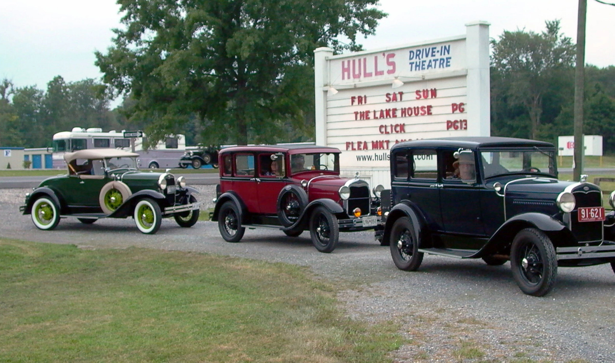 vintage cars in front of the hull’s drive in sign 