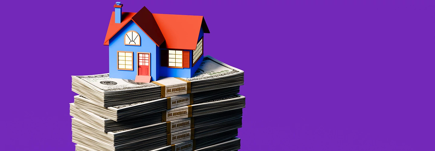 A house sits on top of a stack of money.