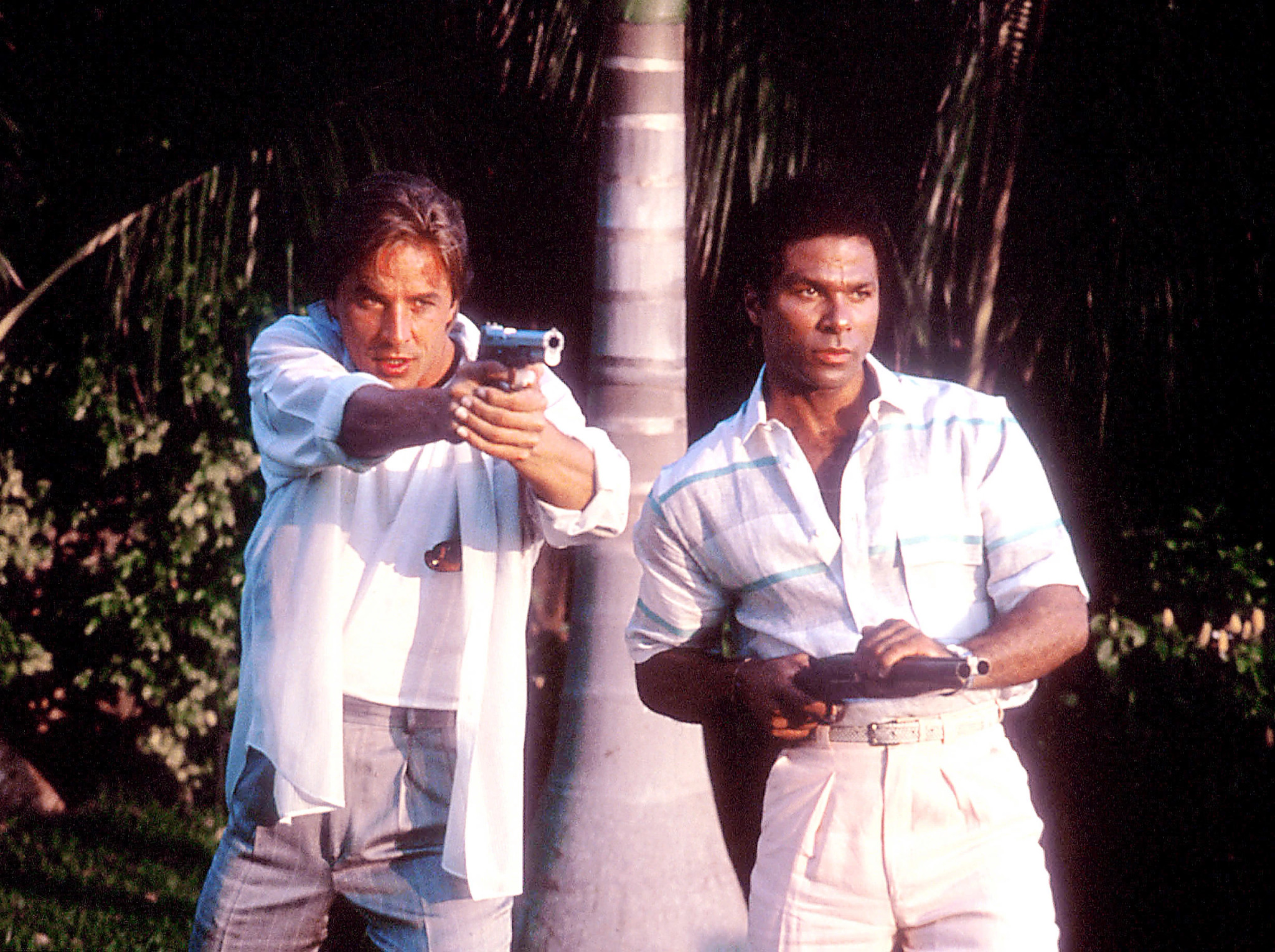 Don Johnson and Philip Michael Thomas both holding guns in a scene from the television series Miami Vice