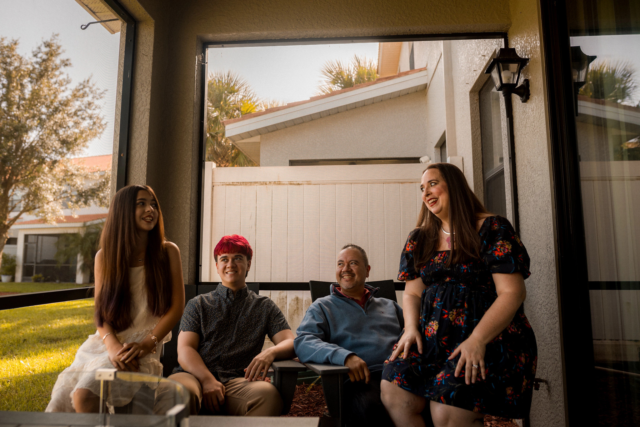 Four family members gather on a screened patio outside a residential home