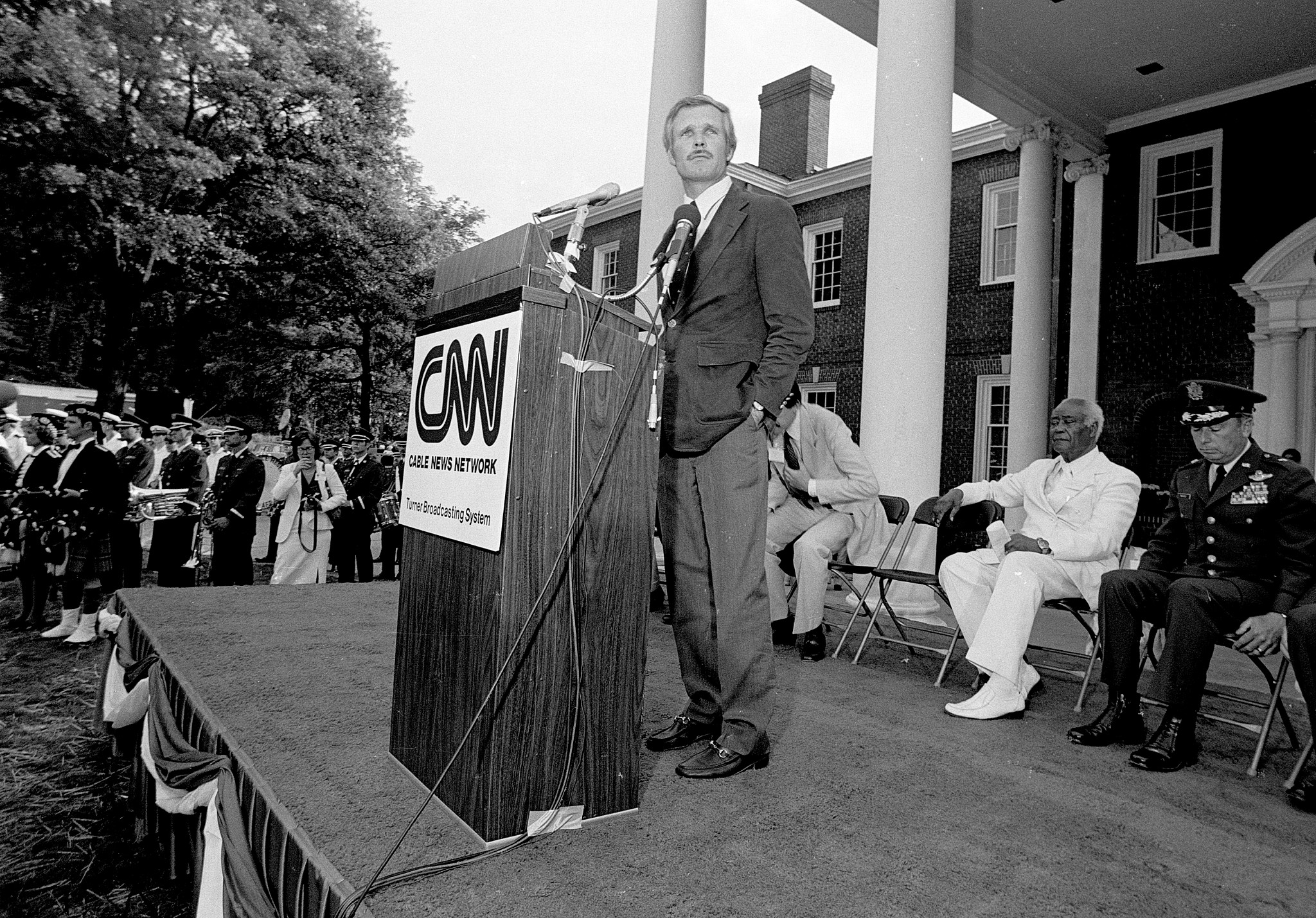 ted turner speaking at a podium in a black and white photo