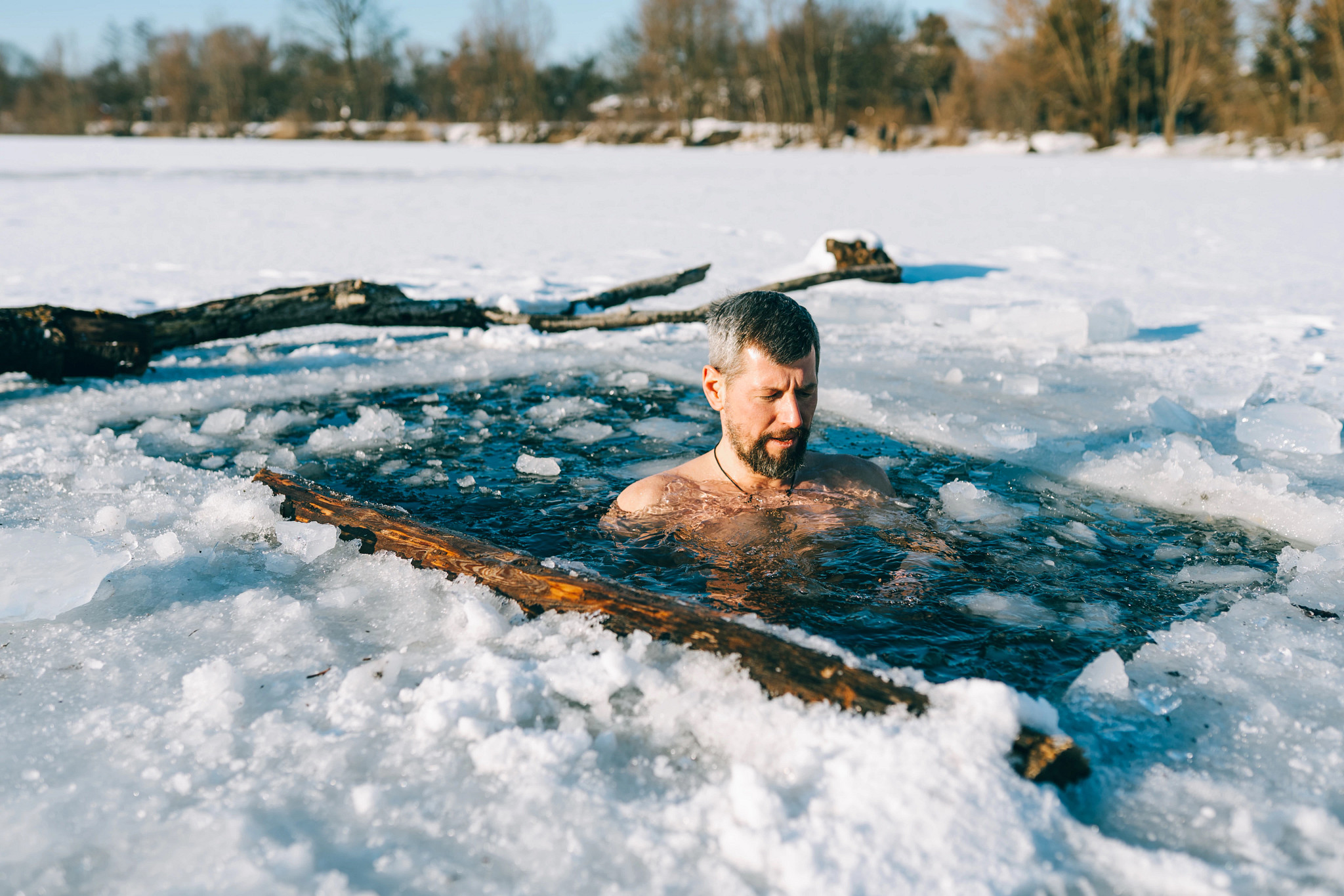 a man sits in an ice bath in a frozen lake