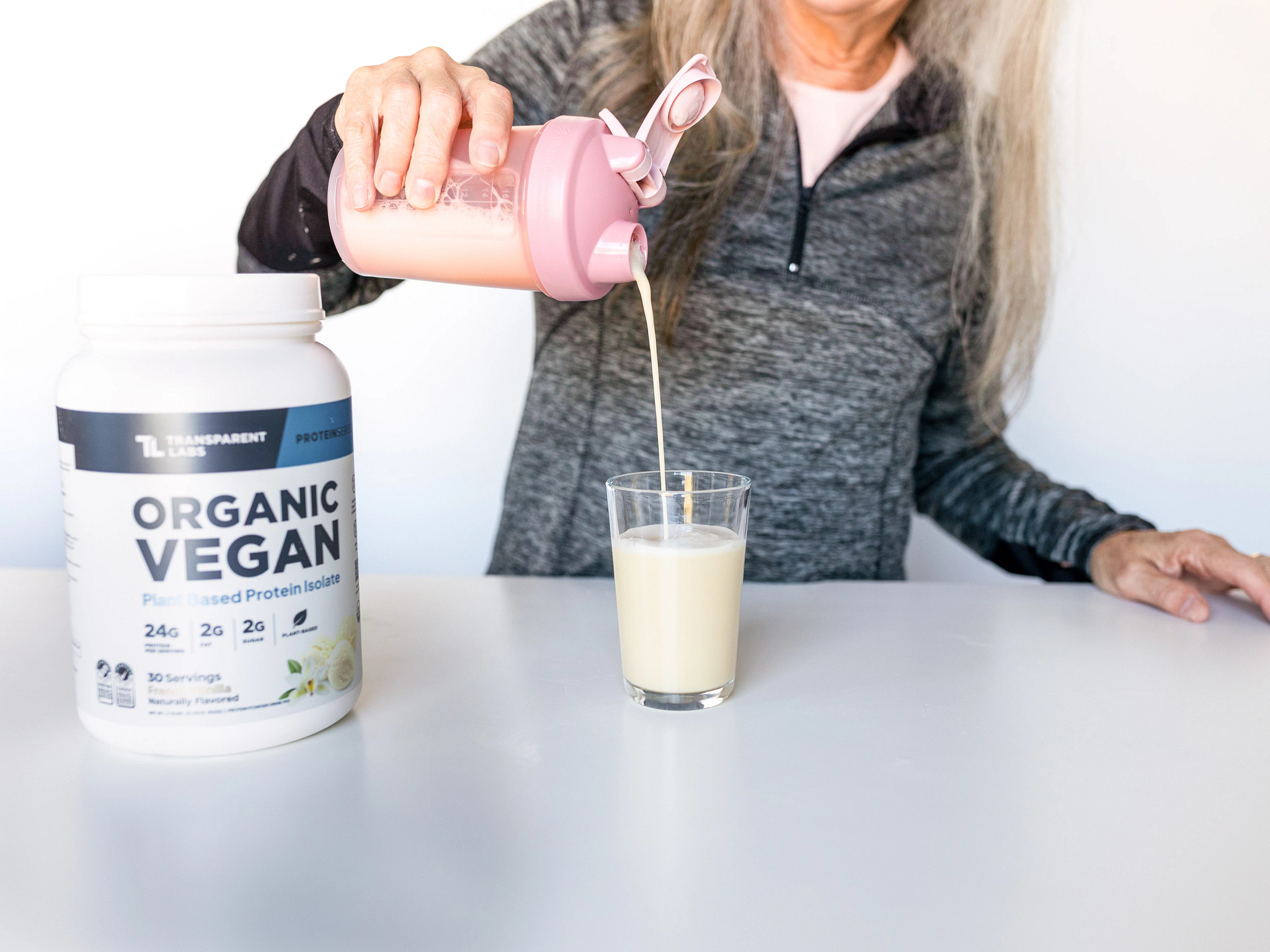 A woman pours the Transparent Labs Organic Vegan Plant-Based Protein drink into a glass