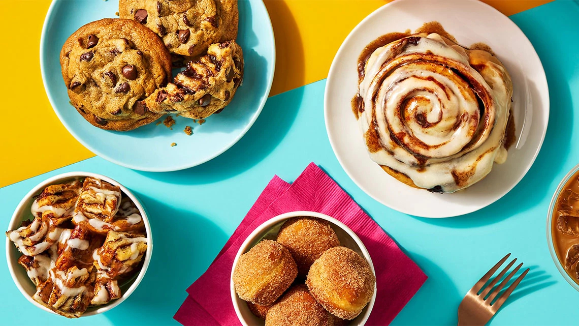 Cinnabon chocolate chip cooks, cinnamon roll bites, donut holes, cinnamon roll whole on a plate