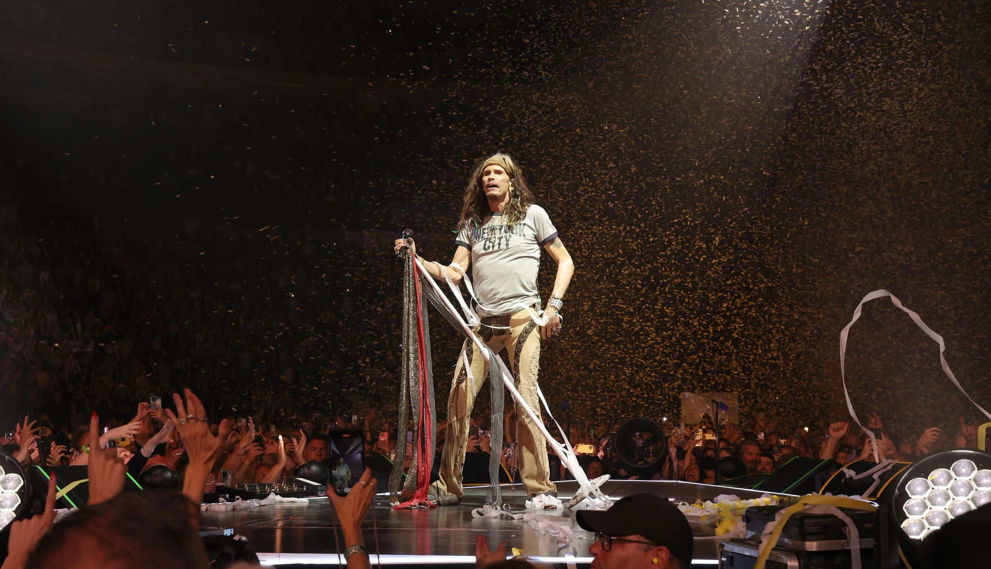 Steven Tyler Steven Tyler standing onstage holding the microphone stand during Aerosmith's performance at UBS Arena in Elmont New York