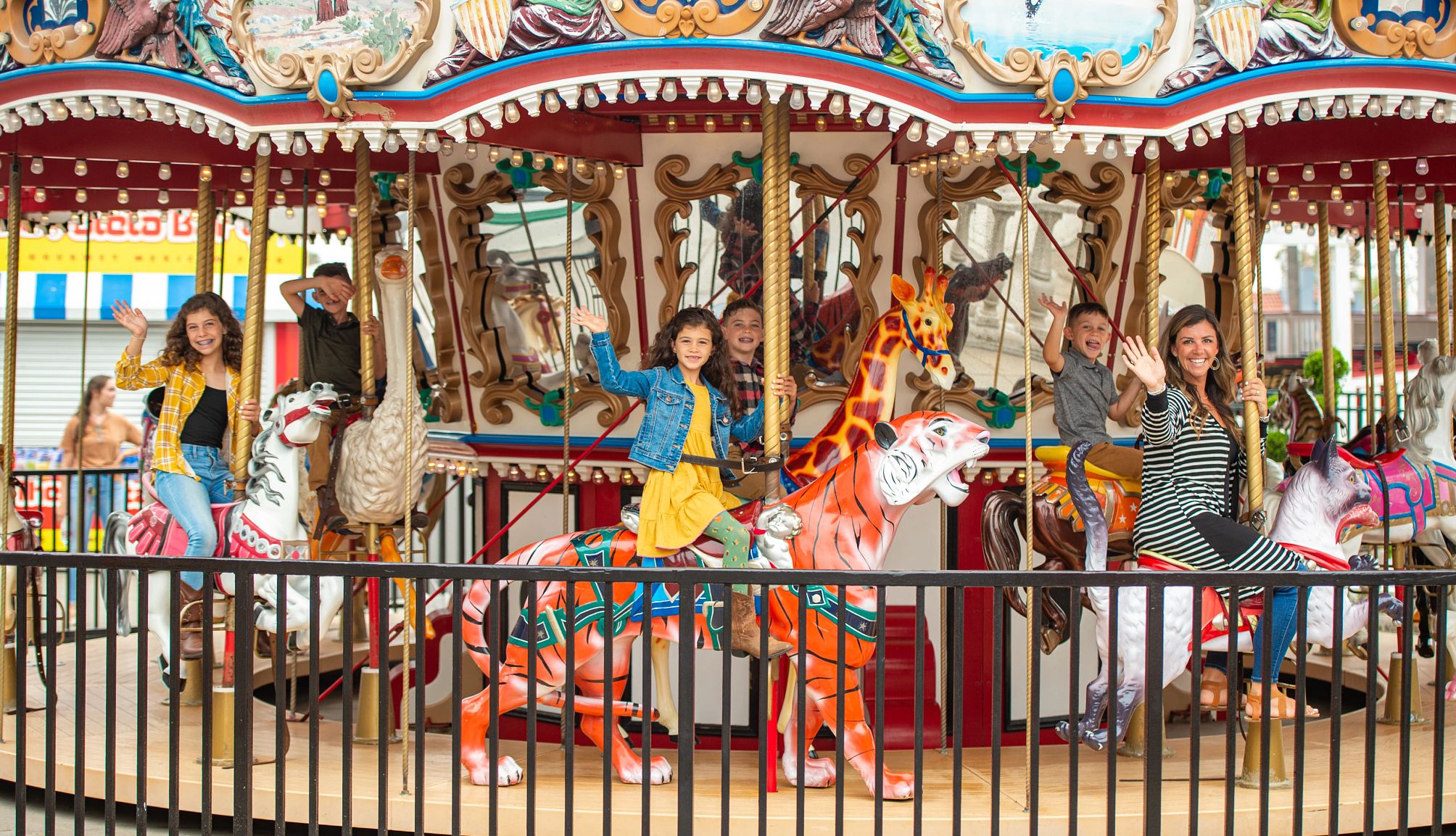 una familia saluda mientras monta en un carrusel en Belmont Park