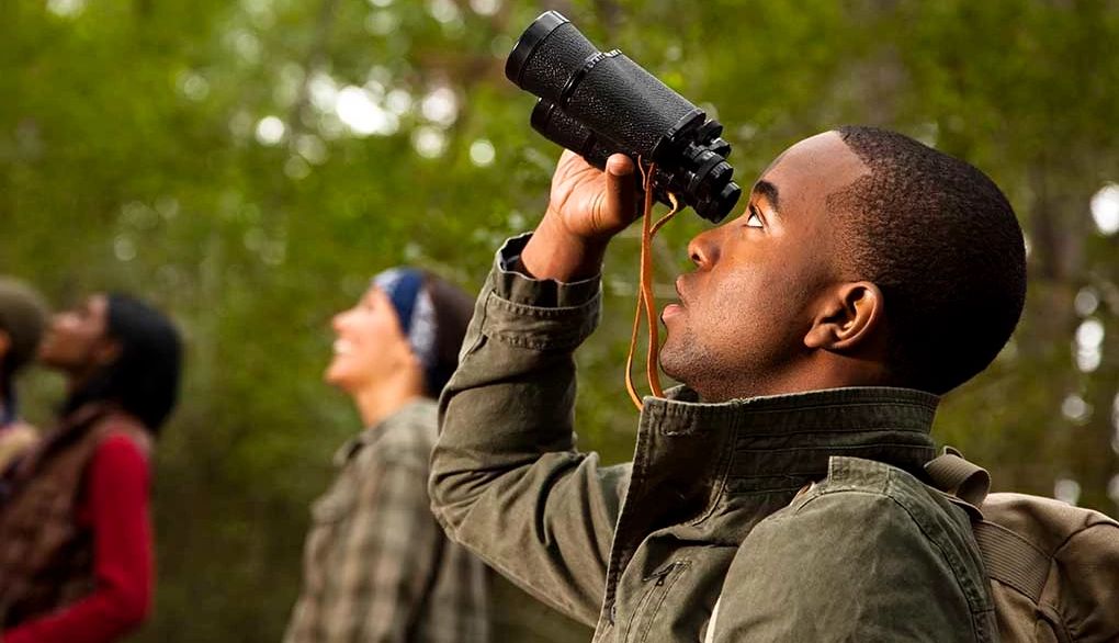 Outdoor walks can be made more meaningful by observing what you see A man using binoculars on a hike with other people