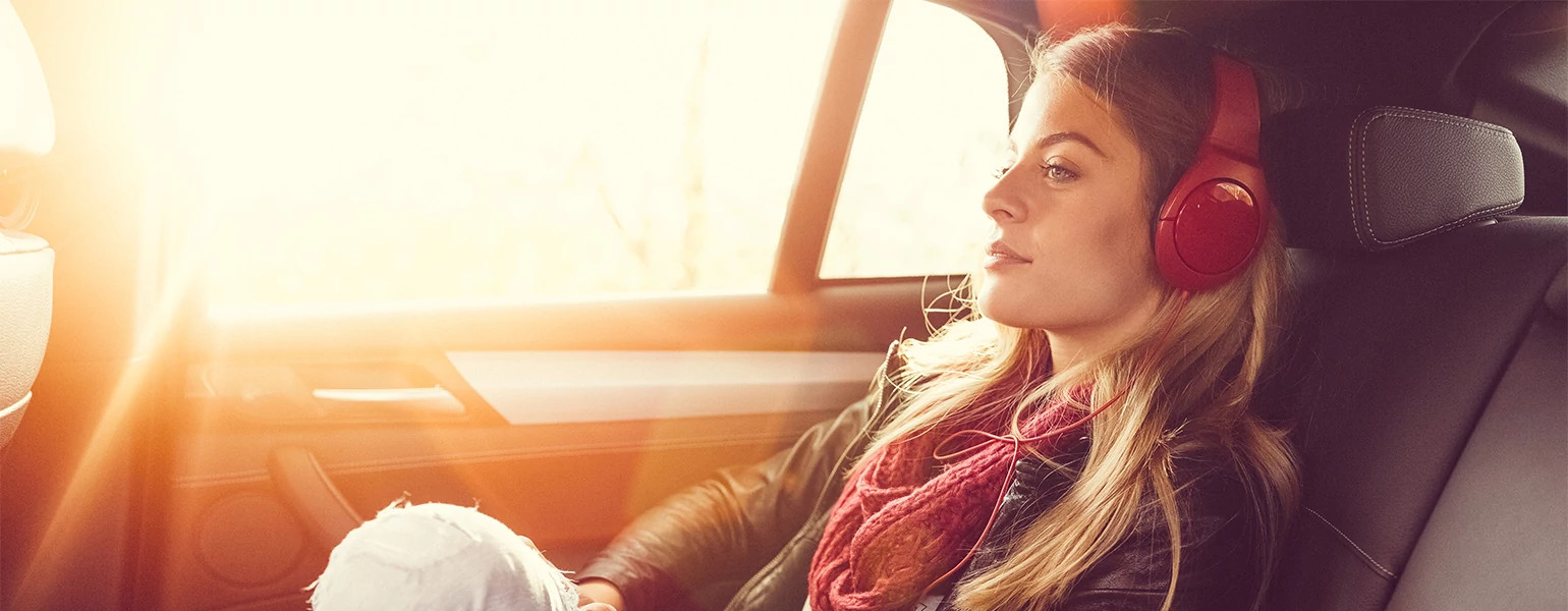 Woman sitting in the back seat of an Uber with headphones on