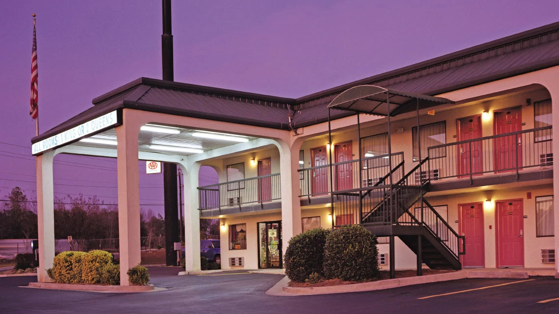 Rodeway Inn® motel entrance outside area to park under in front of door to lobby, outside entrance to multiple rooms and stairway to second floor
