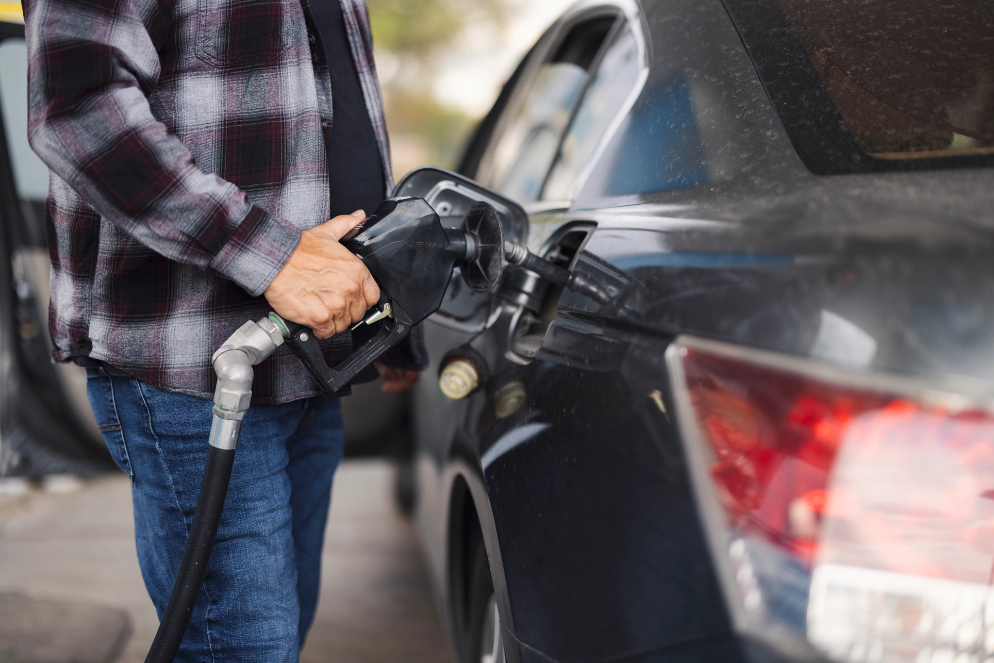 a closeup of a person pumping gas into a car 