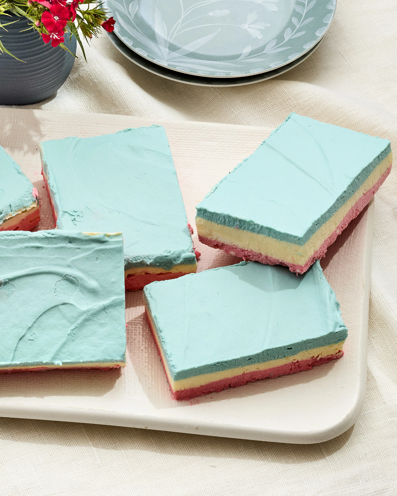 Red, White and Blue Frozen Cashew Cheesecake Bars, five total, are pictured on a plate.