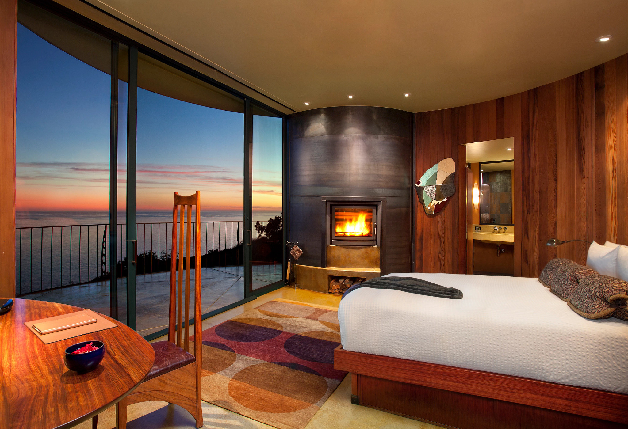 a relaxing hotel room with wood accents, a fireplace and balcony