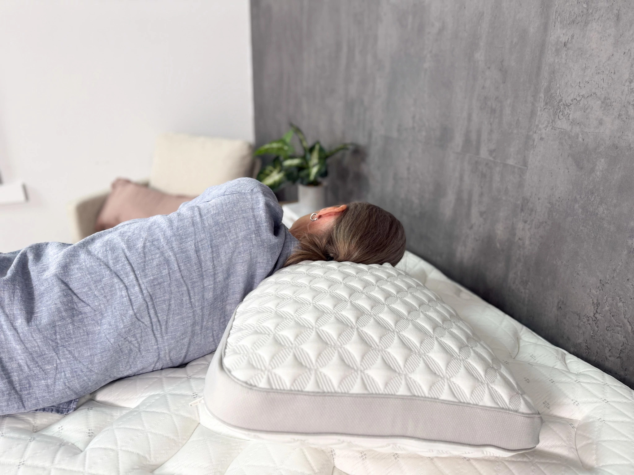 A woman lying on her side on a bed with her head resting on the Brooklyn Bedding Talalay Latex Pillow