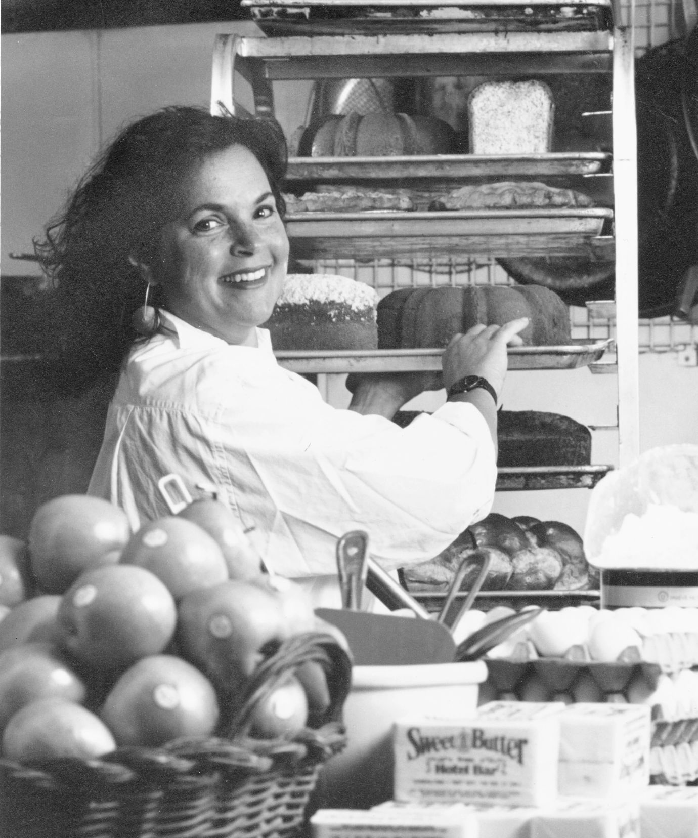Ina Garten with all sorts of food Black and white photo of Ina Garten in a kitchen surrounded by food