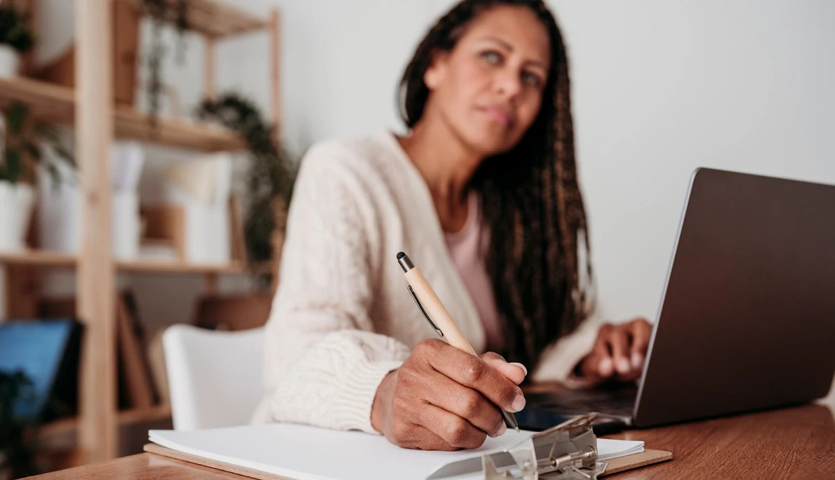 A woman looks deep in thought as she works at her desk.