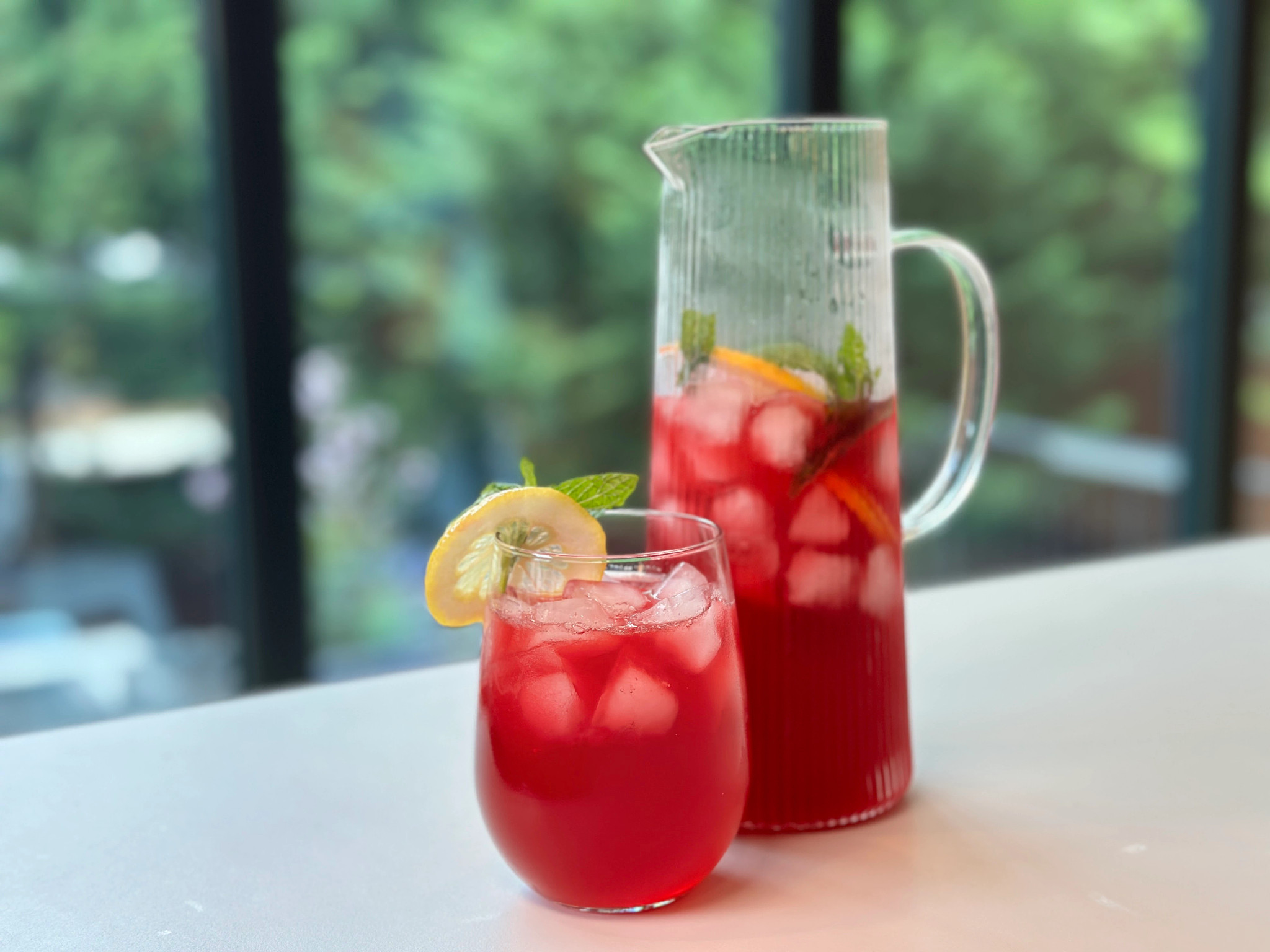 Pitcher of hibiscus ginger sweet tea soda; glass of the drink next to it