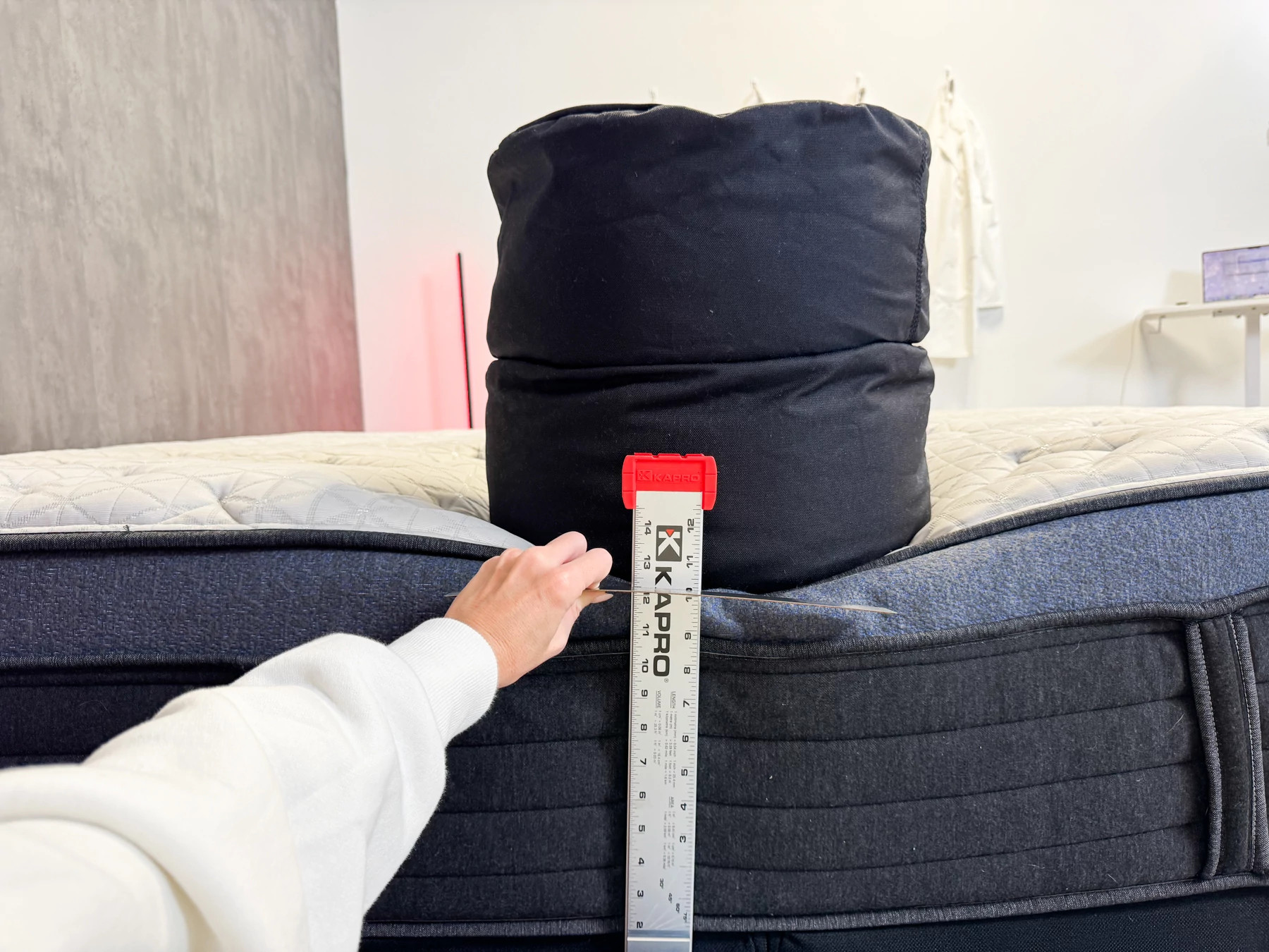 Woman measures how much the edge of a bed sinks under a heavy sandbag