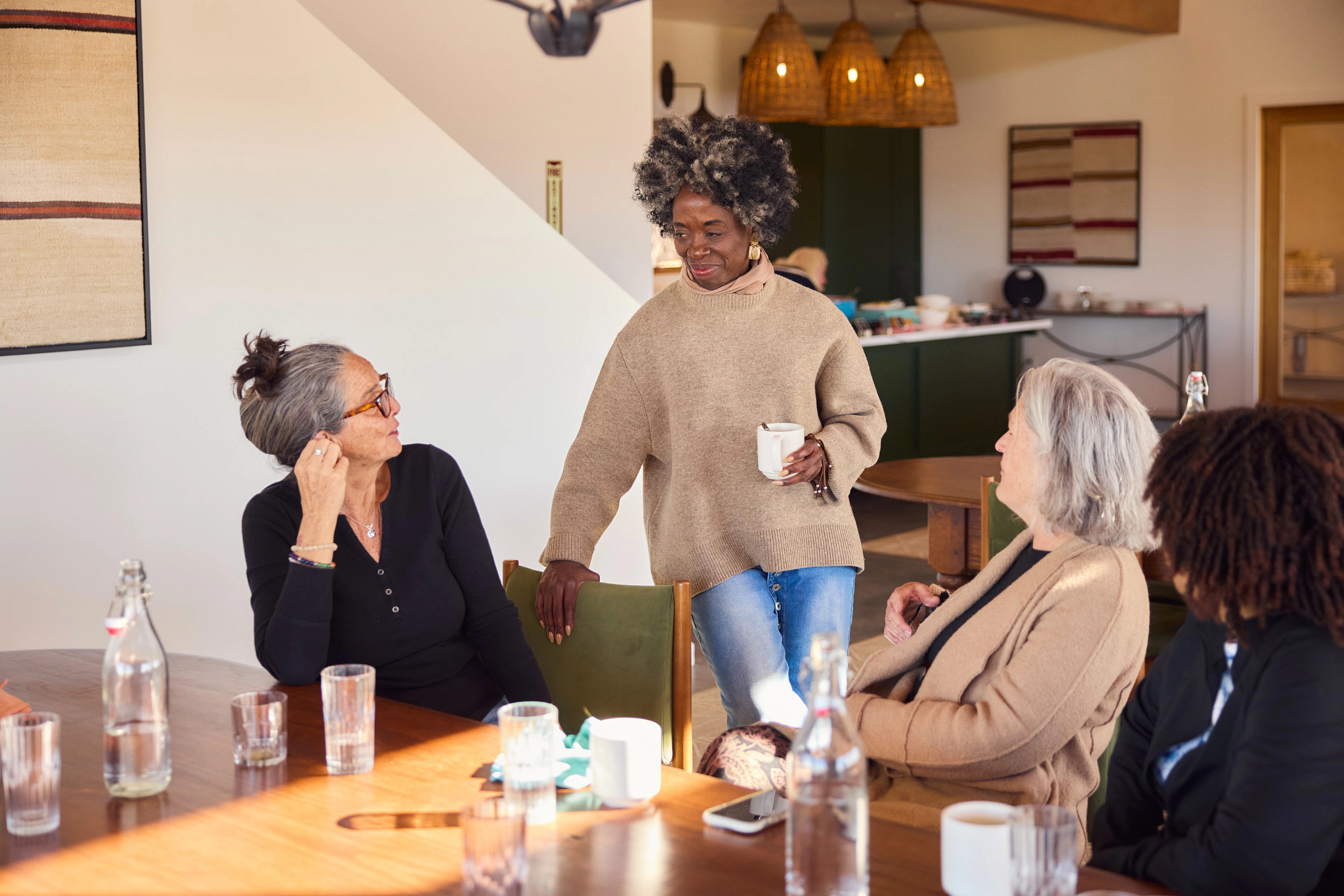 a photo shows participants Jodi Brown, Martha Morrill and Verna Avery Brown chatting with facilitator Elizabeth White after breakfast.