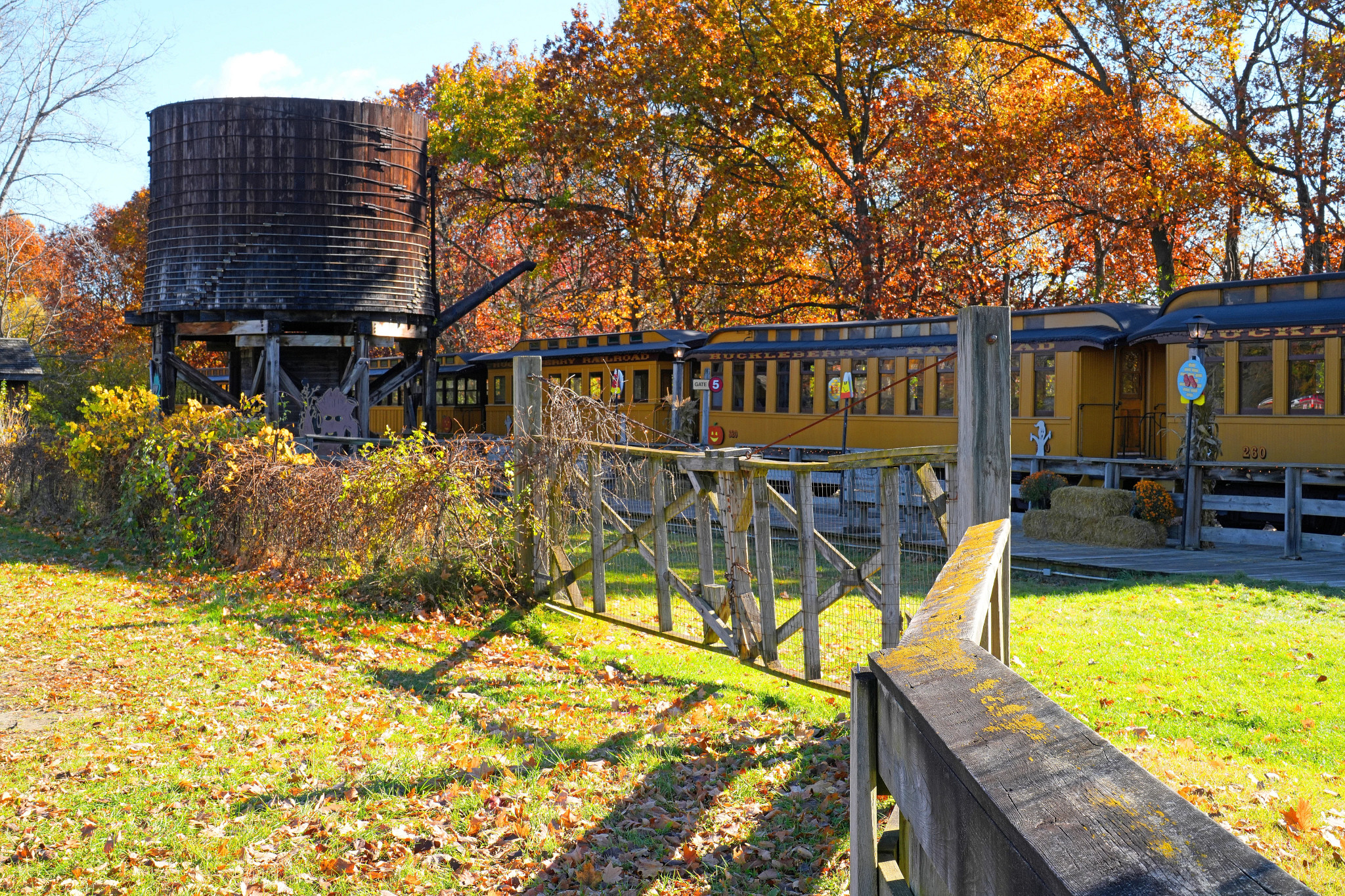a train stopped at a station near a wooden water tower