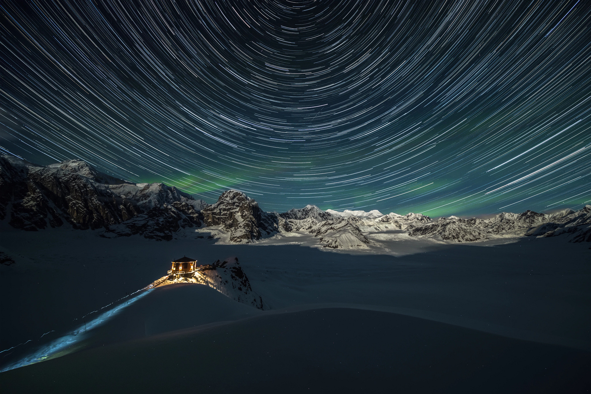 light streaks in the sky with a chalet in the foreground