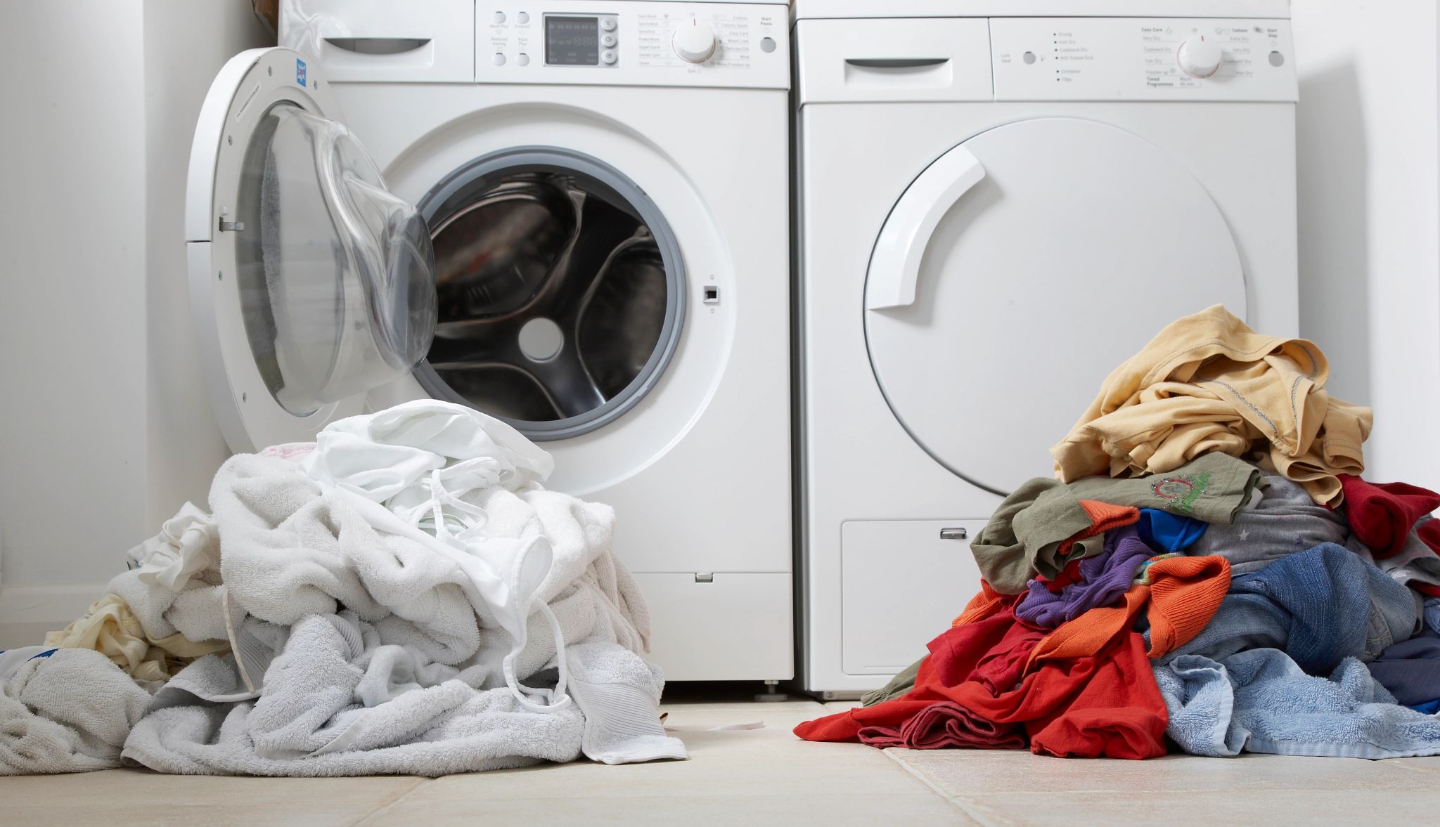 AARP Smart Guide to Laundry clothes piled outside a washing machine and dryer